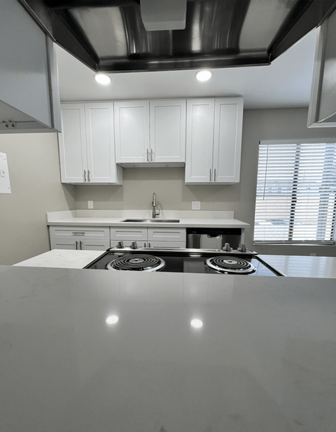 A modern kitchen with white cabinets and a stainless steel stove top.